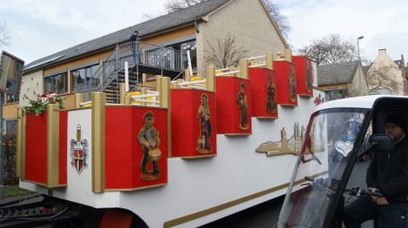 Fahrzeug mit dekorativen, roten Paneelen und Figuren entlang der Seite.